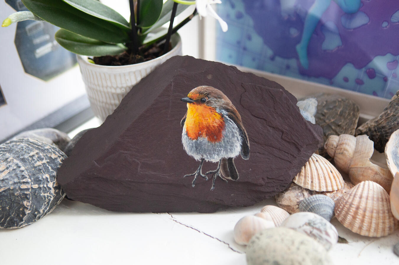 A fluffy little robin painted on a piece of plum slate.